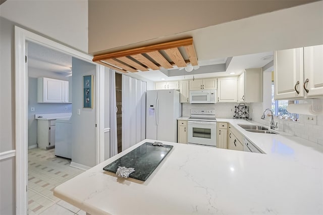 kitchen featuring sink, white appliances, tasteful backsplash, a raised ceiling, and kitchen peninsula