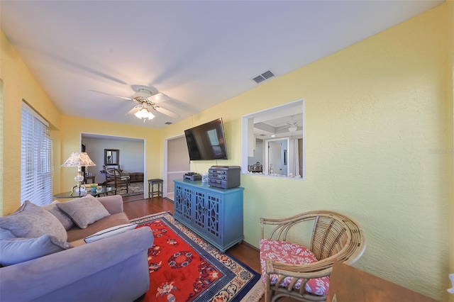 living room with dark wood-type flooring and ceiling fan