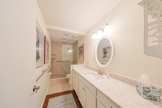 bathroom featuring tiled shower, vanity, wood-type flooring, a textured ceiling, and toilet