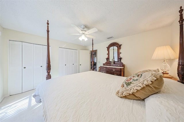 bedroom featuring ceiling fan, carpet flooring, a textured ceiling, and two closets