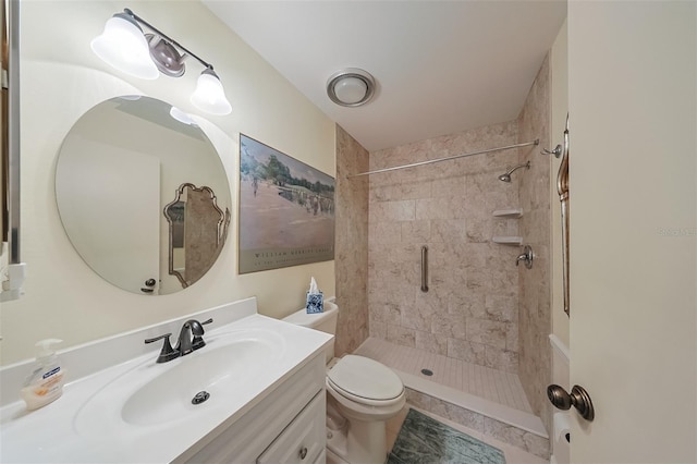 bathroom featuring tiled shower, vanity, and toilet