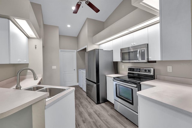 kitchen with ceiling fan, washer and dryer, light hardwood / wood-style floors, white cabinetry, and stainless steel appliances