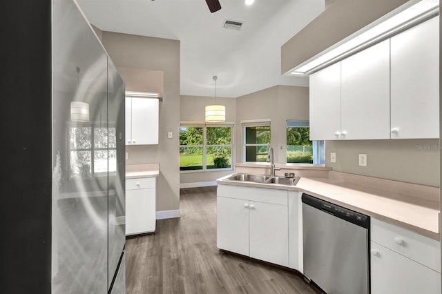 kitchen featuring appliances with stainless steel finishes, light wood-type flooring, sink, decorative light fixtures, and white cabinetry