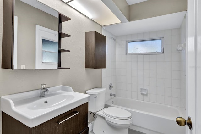 full bathroom featuring vanity, tiled shower / bath combo, and toilet