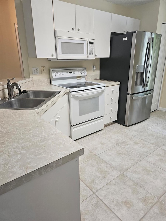 kitchen with white appliances, white cabinetry, sink, and light tile patterned floors