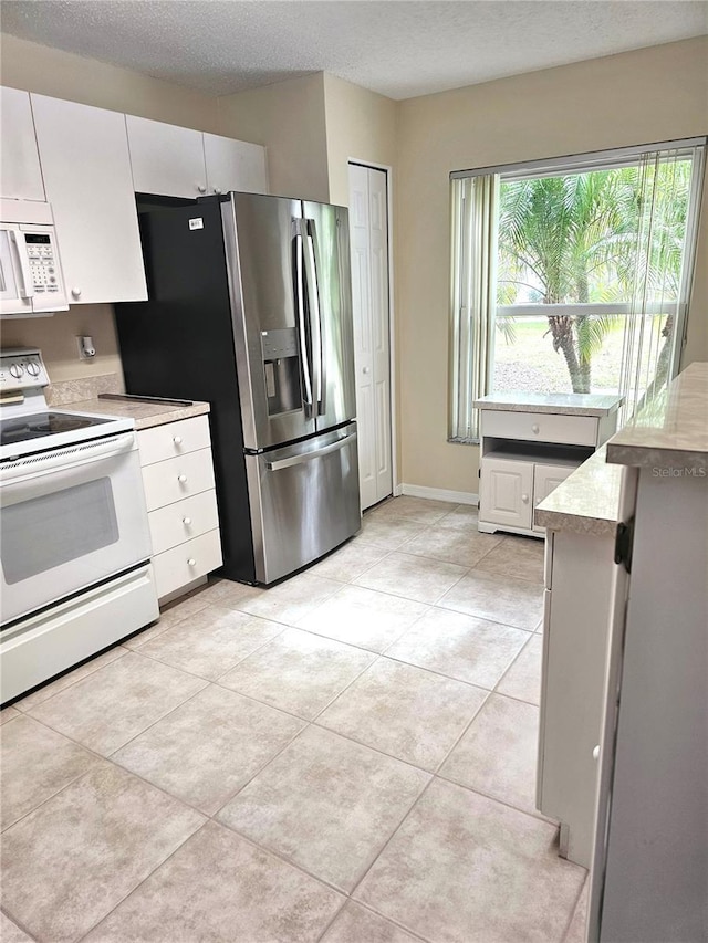 kitchen featuring white appliances, white cabinetry, a textured ceiling, and light tile patterned floors