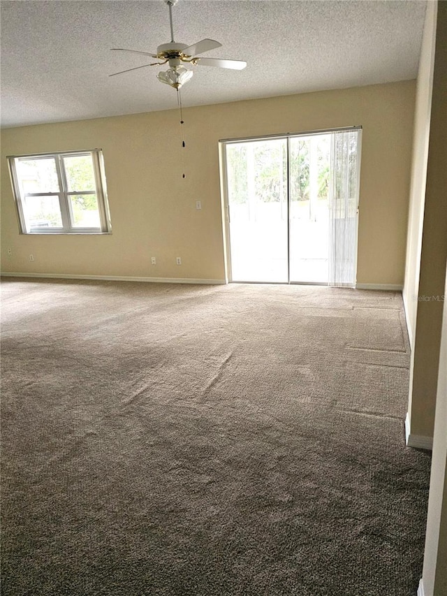 carpeted empty room featuring ceiling fan and a textured ceiling