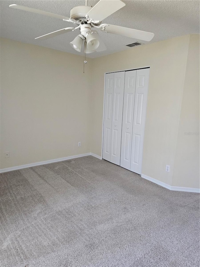 unfurnished bedroom with a textured ceiling, a closet, ceiling fan, and carpet