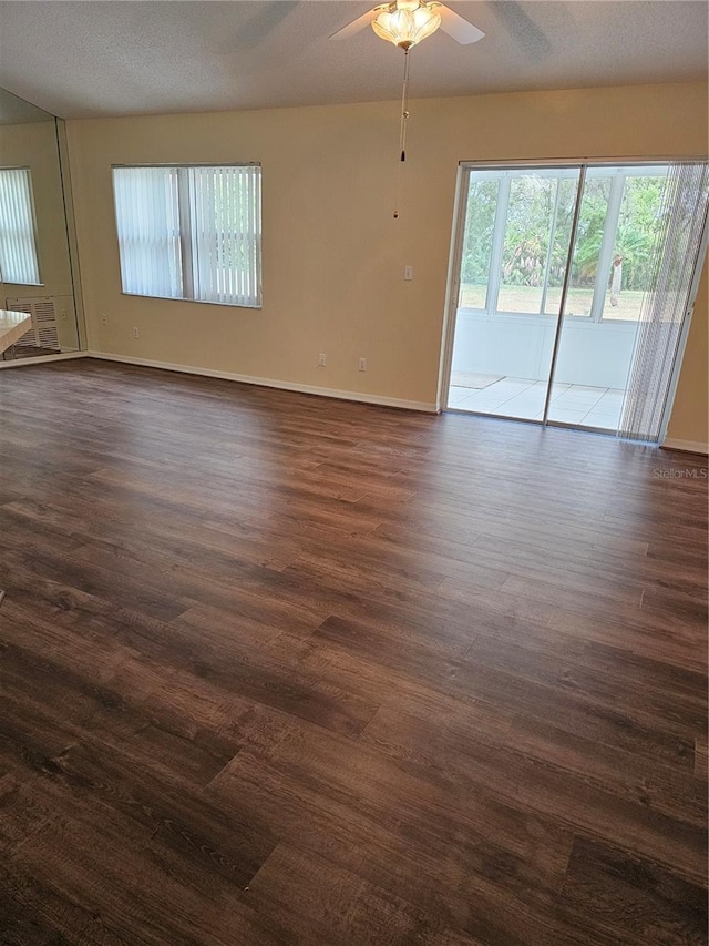 spare room with baseboards, a textured ceiling, a ceiling fan, and dark wood-style flooring