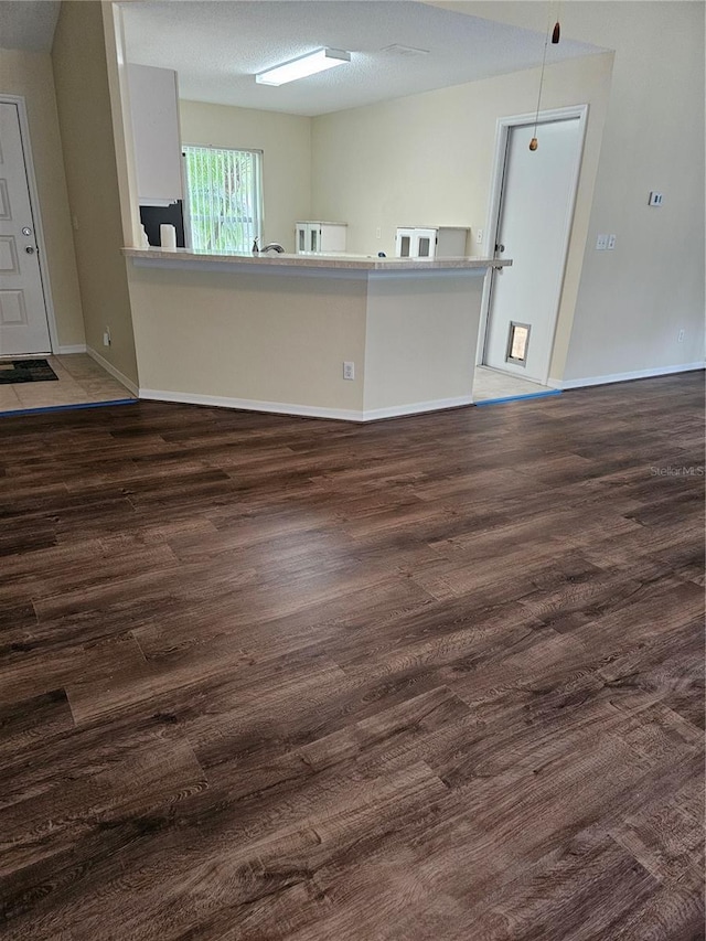 interior space featuring a textured ceiling, wood finished floors, and baseboards