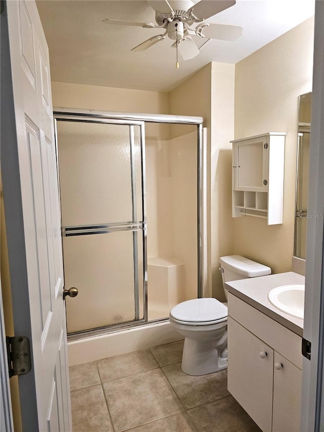 bathroom featuring ceiling fan, tile patterned flooring, toilet, vanity, and a stall shower