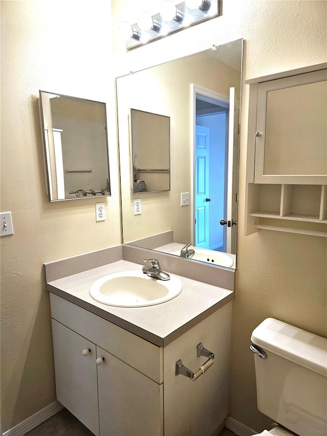 bathroom featuring a textured wall, vanity, and toilet