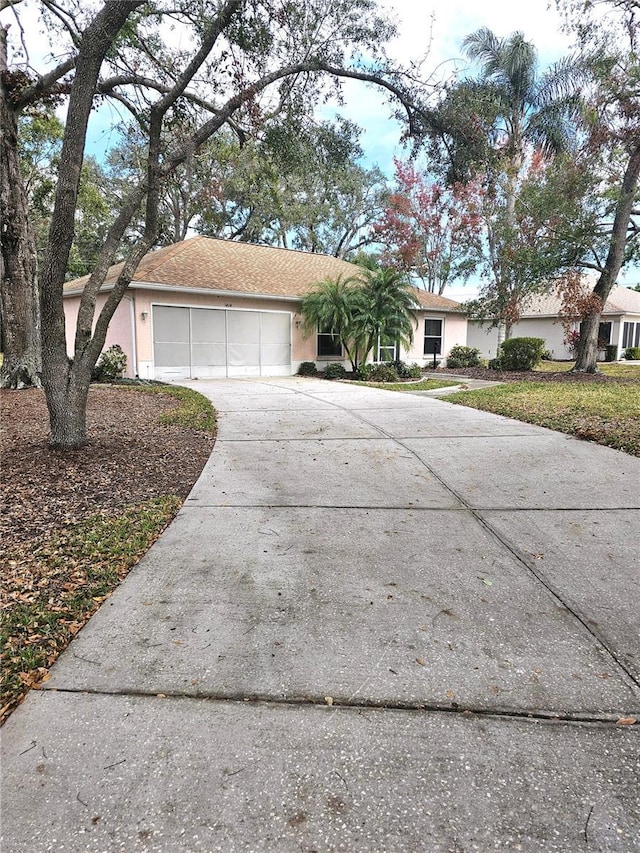 ranch-style house featuring concrete driveway, an attached garage, and stucco siding