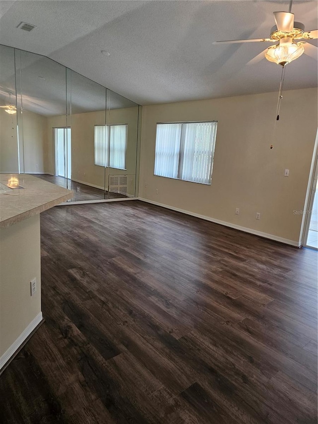 empty room featuring vaulted ceiling, dark wood-style floors, visible vents, and ceiling fan