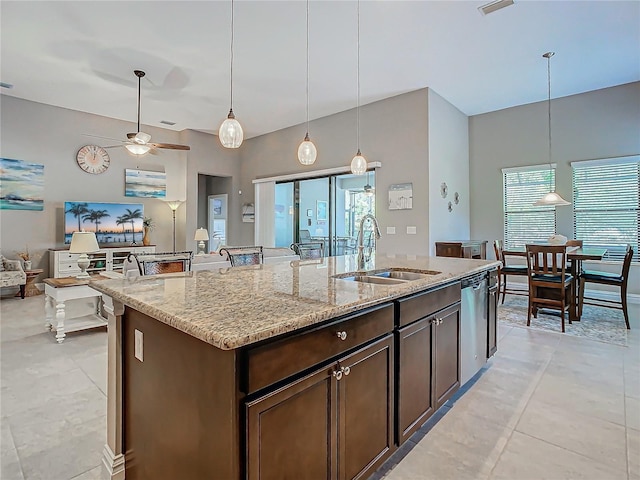 kitchen featuring light stone counters, dishwasher, hanging light fixtures, sink, and dark brown cabinetry