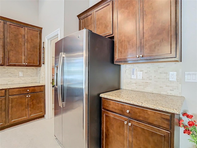 kitchen with light stone countertops, tasteful backsplash, and stainless steel fridge