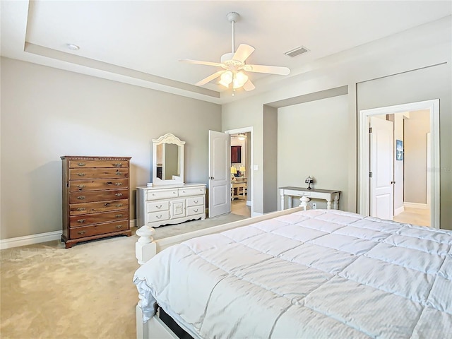 bedroom featuring light colored carpet, ceiling fan, and a tray ceiling