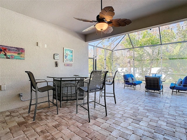 view of patio with ceiling fan and glass enclosure