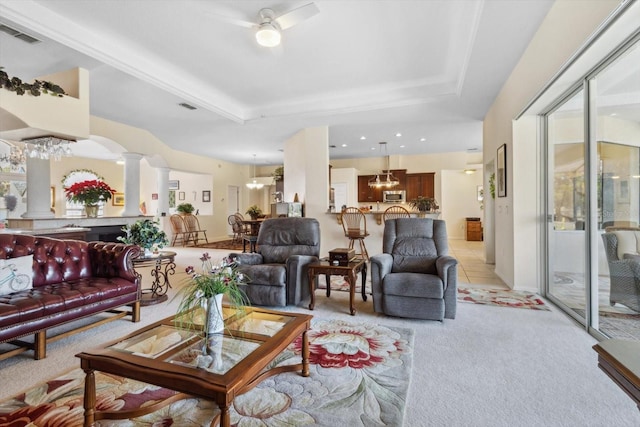 living room with ceiling fan, ornate columns, light carpet, and a tray ceiling