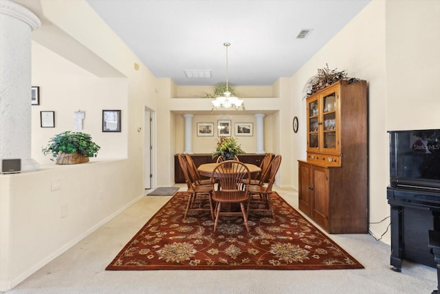 carpeted dining space featuring an inviting chandelier and ornate columns