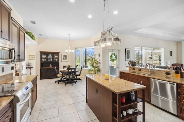 kitchen featuring pendant lighting, a center island, sink, light stone countertops, and a chandelier