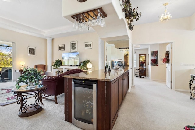 kitchen with ornate columns, wine cooler, light stone counters, pendant lighting, and light colored carpet