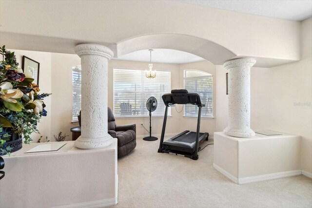 exercise room with a notable chandelier, light colored carpet, and ornate columns