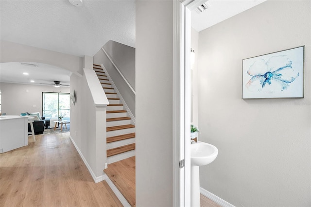 staircase featuring wood-type flooring and ceiling fan