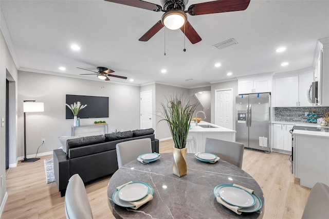 dining room featuring sink, light hardwood / wood-style floors, and crown molding