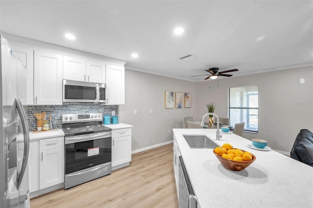 kitchen featuring stainless steel appliances, white cabinets, decorative backsplash, and sink