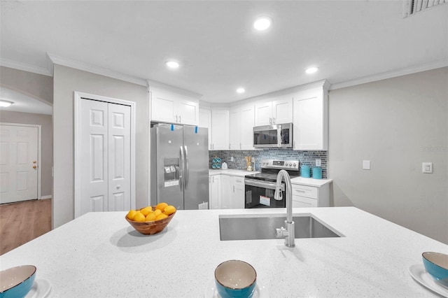 kitchen with white cabinets, stainless steel appliances, decorative backsplash, and sink