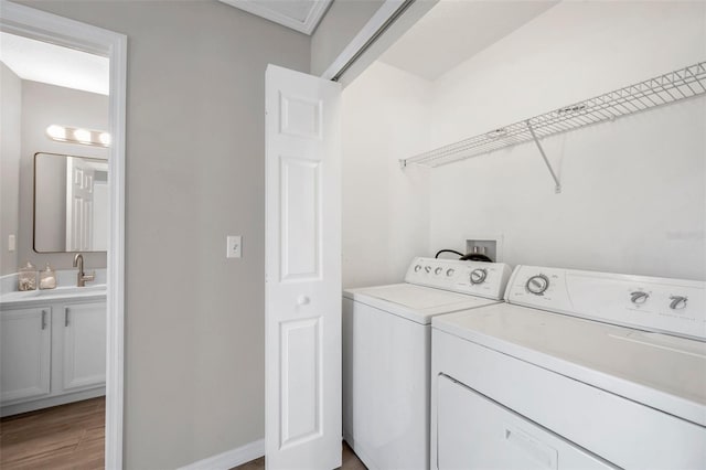 laundry area featuring light wood-type flooring, washing machine and dryer, and sink