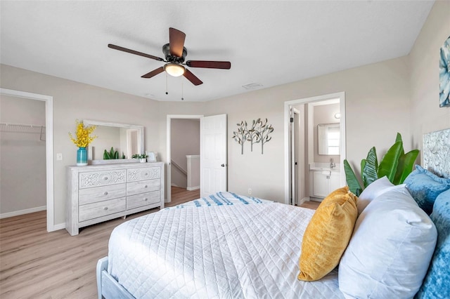 bedroom with connected bathroom, ceiling fan, light hardwood / wood-style flooring, a closet, and a walk in closet