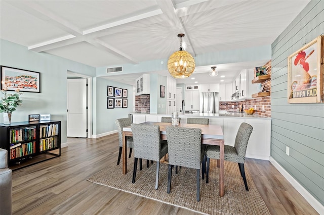 dining space featuring hardwood / wood-style flooring, coffered ceiling, beam ceiling, and wood walls