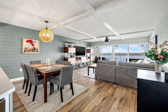 dining space with coffered ceiling, light wood-type flooring, wooden walls, ceiling fan, and beam ceiling