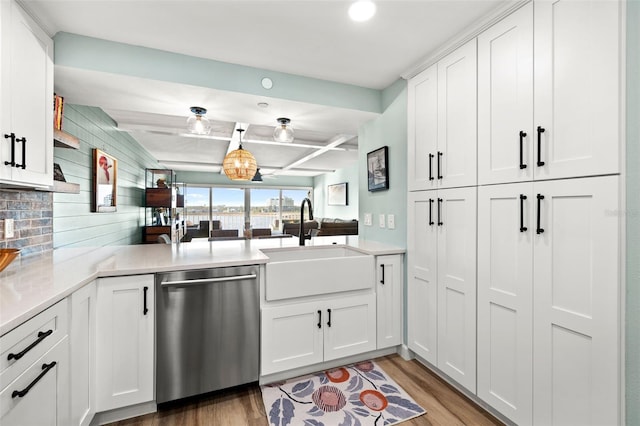 kitchen featuring sink, wood-type flooring, stainless steel dishwasher, beamed ceiling, and white cabinets