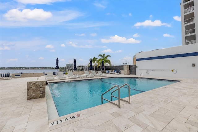 view of swimming pool with a water view and a patio