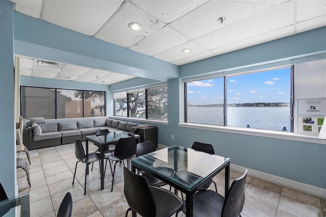 dining room featuring a paneled ceiling, a healthy amount of sunlight, and a water view