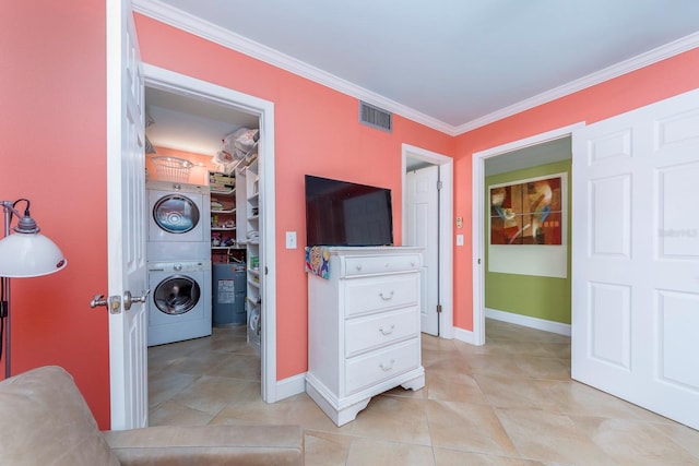 interior space with light tile patterned flooring, stacked washer / dryer, ornamental molding, a spacious closet, and a closet