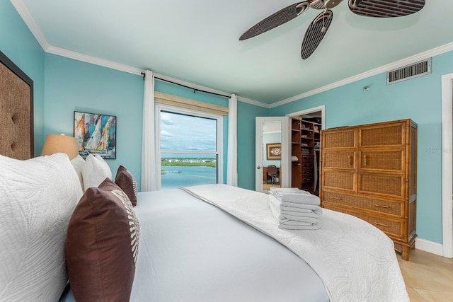 bedroom featuring ceiling fan, a walk in closet, ornamental molding, and a closet