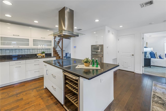 kitchen featuring appliances with stainless steel finishes, white cabinets, a center island, wine cooler, and island range hood