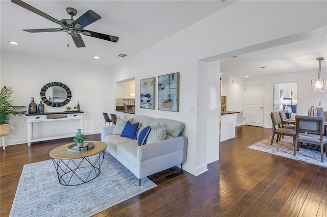 living room featuring dark wood-type flooring and ceiling fan