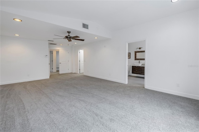 spare room featuring ceiling fan, light carpet, and vaulted ceiling