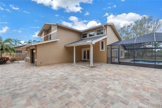 rear view of house with glass enclosure, a patio area, and french doors