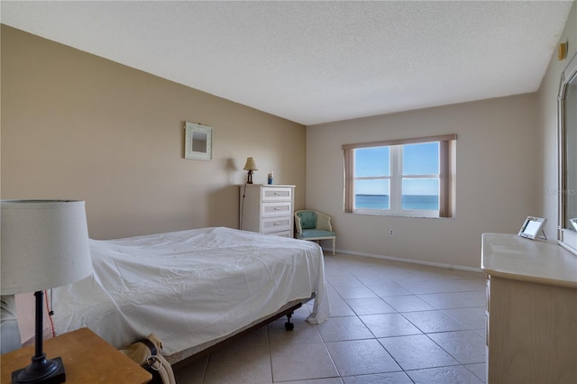 tiled bedroom featuring a textured ceiling and a water view