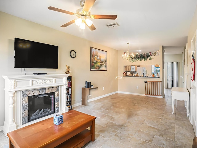 living room featuring ceiling fan with notable chandelier and a tiled fireplace