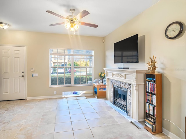 tiled living room featuring a high end fireplace and ceiling fan