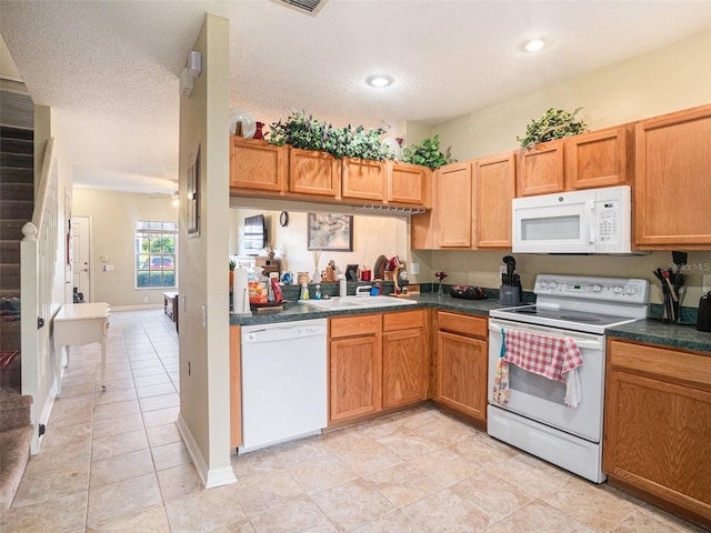 kitchen featuring a textured ceiling, light tile patterned flooring, white appliances, and sink