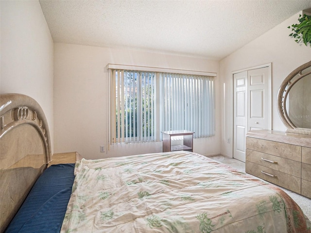 bedroom featuring a textured ceiling, a closet, and lofted ceiling