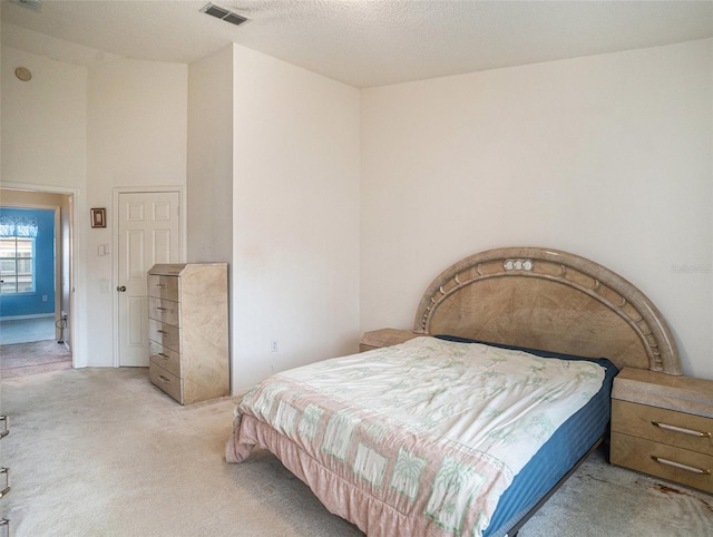 bedroom featuring light colored carpet and a textured ceiling